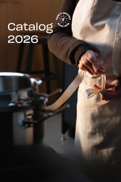 A person in a white apron ties the belly band next to a high-quality Fissler stainless steel pot. "Catalog 2026" is at the top left.