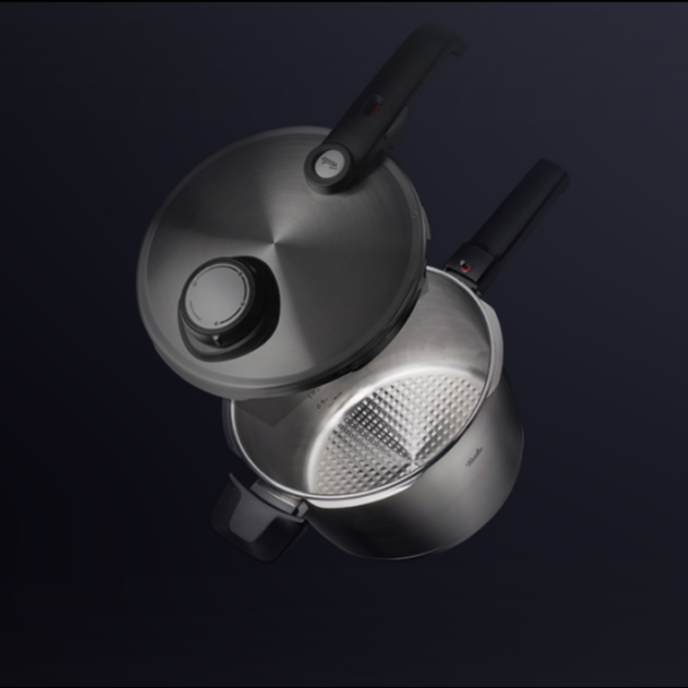 Fissler stainless steel pressure cooker with black handle. The lid is partially open, revealing the precisely structured interior made in Germany.
