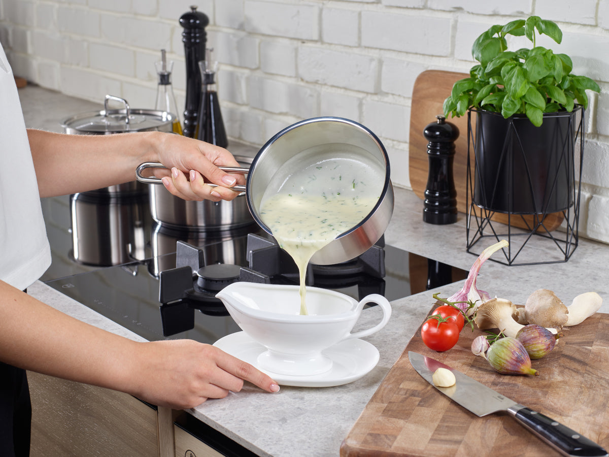 The creamy herb soup is poured from a 16 cm pot made of recycled stainless steel from the Fissler Pure Collection, showcasing German engineering.