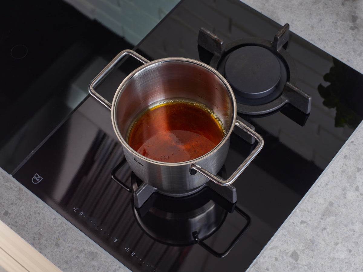 Fissler Pure Collection Cooking Pot with Glass Lid on stove, one burner on. Precision cookware made in Germany, timeless and durable.