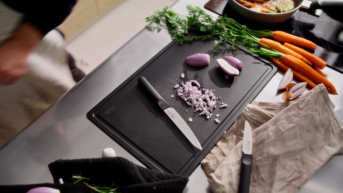 An elegant kitchen counter features the Fissler ProCut Universal Knife 14cm resting next to fresh ingredients on a black cutting board.