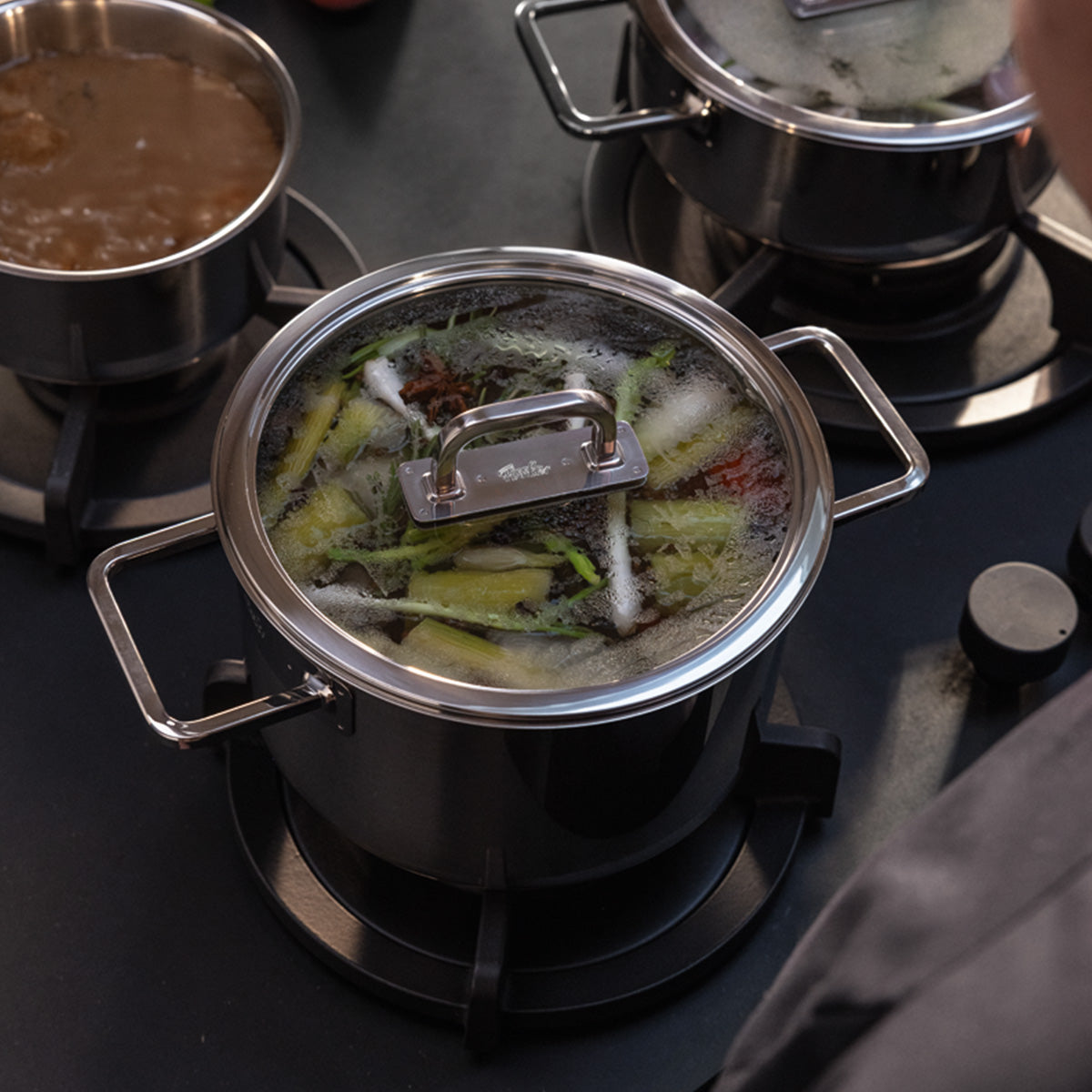 Fissler Viseo® Pro 20 cm pot with glass lid simmering on the stove; other Fissler cookware and saucepans accompany it.