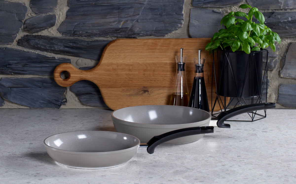 Two Fissler Ceratal® pans (28 cm & 24 cm) with black handles on a kitchen counter. PTFE-free, quality Made in Germany.