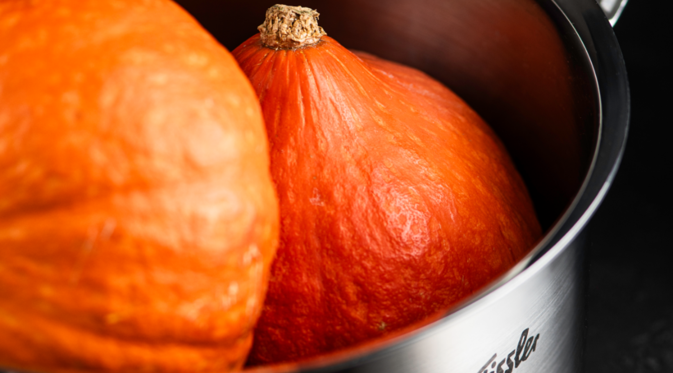 Zwei leuchtend orangefarbene Kürbisse sitzen in einem Fissler-Edelstahltopf und unterstreichen die deutsche Präzision und das zeitlose Design des Topfes.