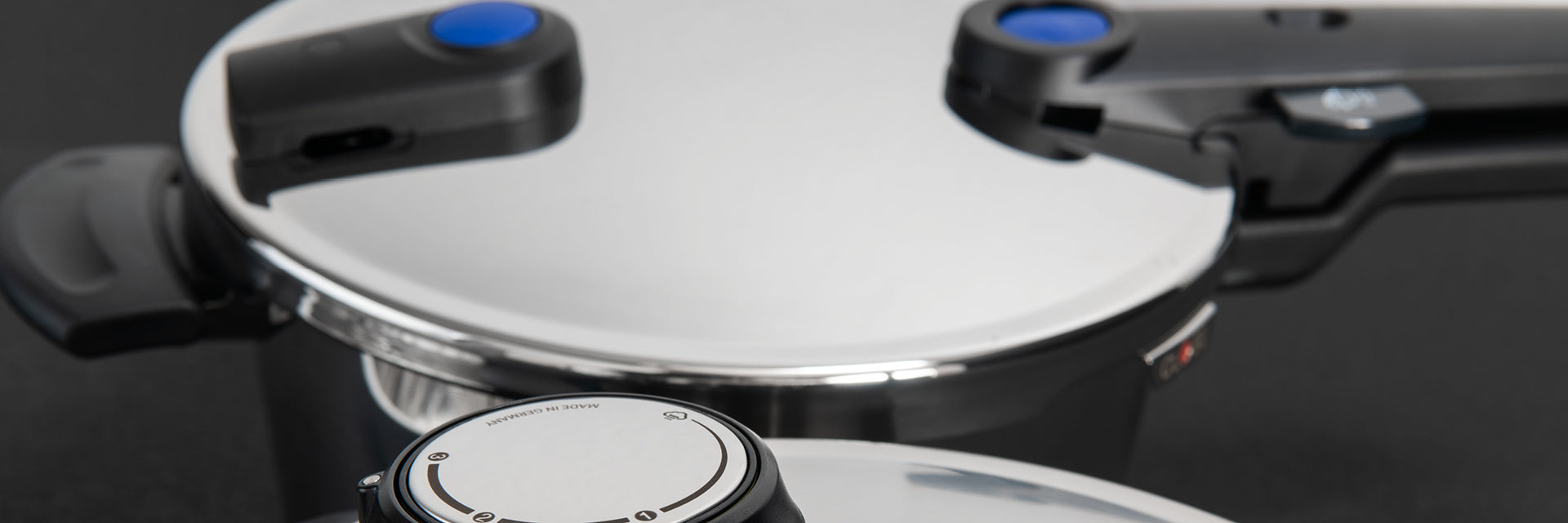 Zwei Fissler Schnellkochtöpfe aus Edelstahl mit schwarzen Griffen und blauen Anzeigen, die für deutsche Präzision und zeitloses Design stehen.