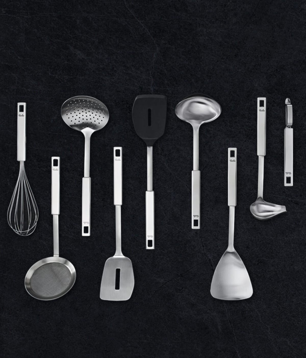 Fissler Stainless Steel Utensil Set - 10 precision-crafted tools, elegantly arranged on a dark background. Made in Germany.