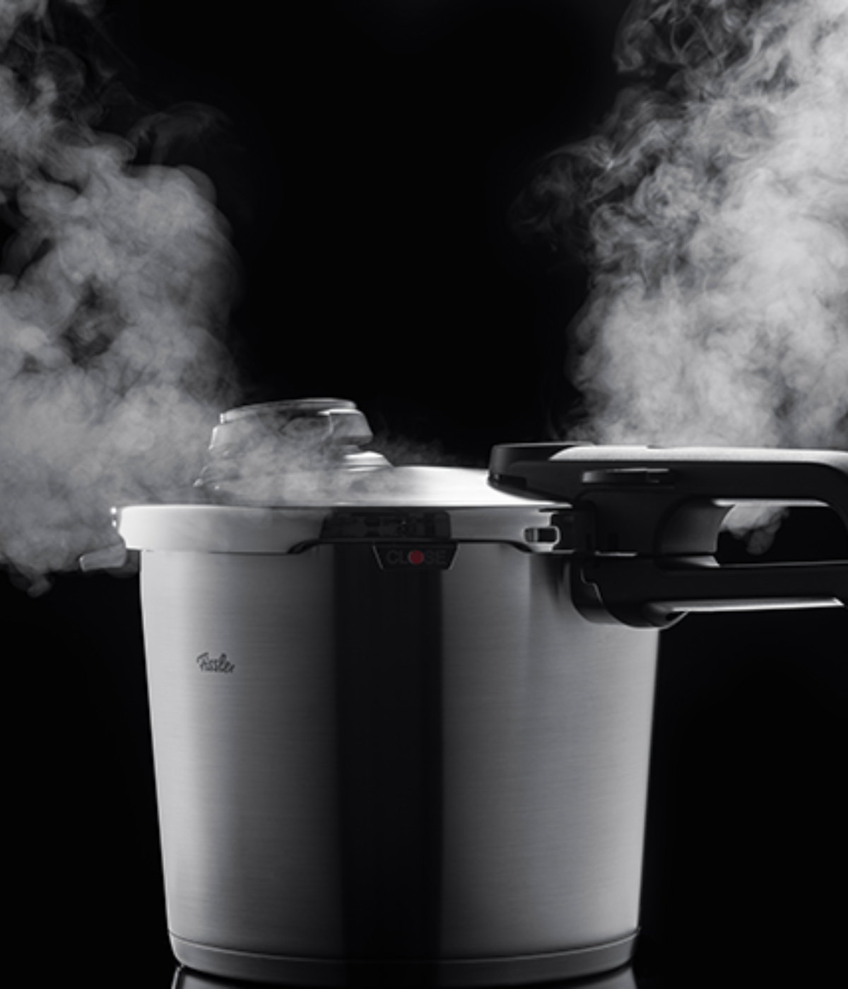 A Fissler stainless steel pressure cooker releases steam, showcasing German precision and innovation against a black background.