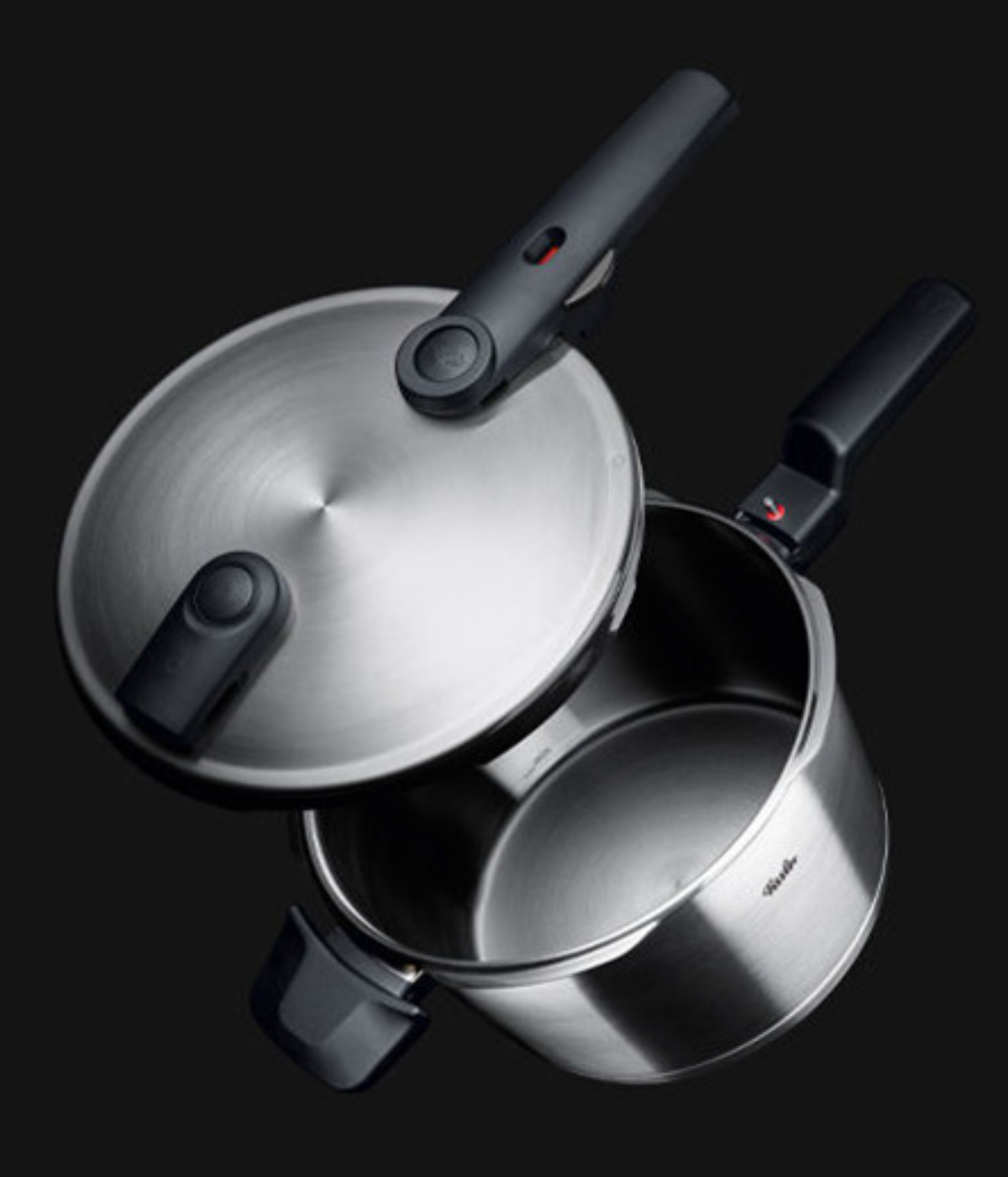 Fissler stainless steel pressure cooker with ergonomic black handles and open lid, shining with German precision and timeless design.